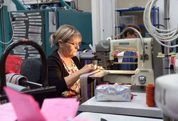 Keltic ties seamstress sewing striped fabric at a machine, one of the uk tie manufacturers producing custom club ties