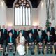 Loughborough male voice choir seated in a church wearing dark blazers and turquoise shirts