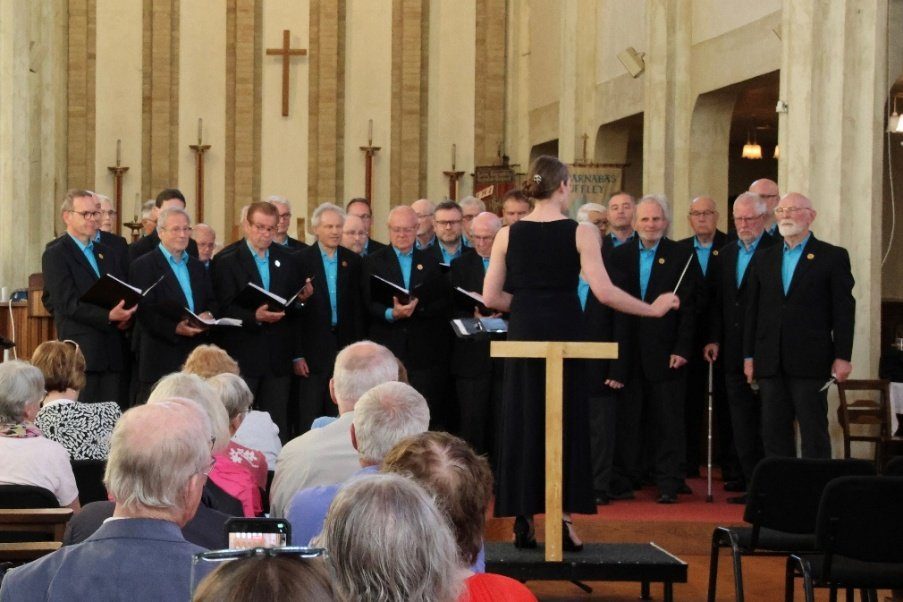 Choir uniform ideas: how loughborough male voice choir found its look | choir uniform ideas Loughborough male voice choir singing in dark blazers and turquoise shirts while their conductor leads